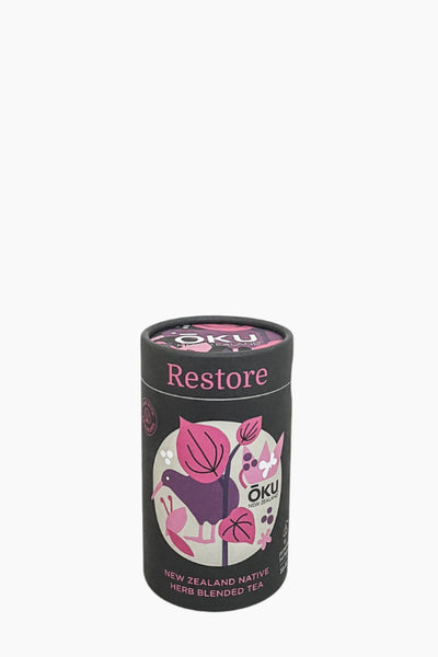A cylindrical container of Oku Herb Blended Tea Restore with illustrations of herbs and a purple bird on the label.