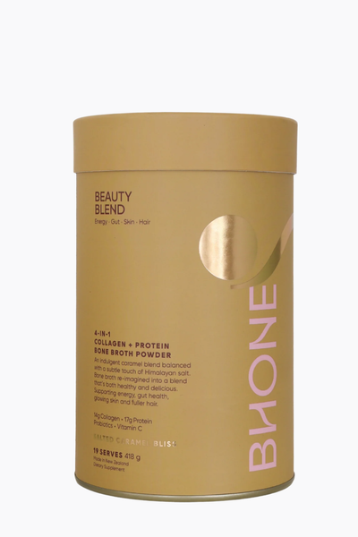 A gold cylindrical container of Bione Beauty Blend Collagen + Protein Bone Broth Powder on a white background.