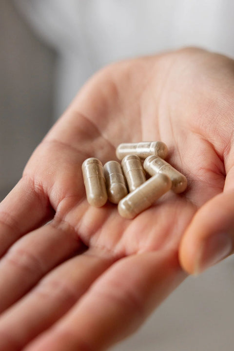 Hand holding several capsules against a blurred background Dr Libby Iron Supplement 
