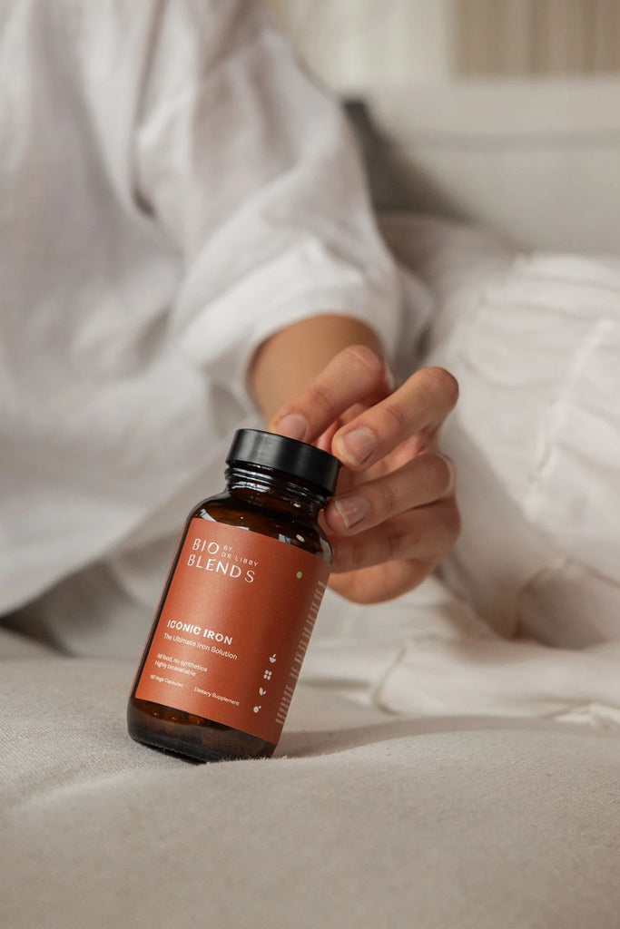Hand holding a supplement bottle labeled 'Blends' Iconic Iron