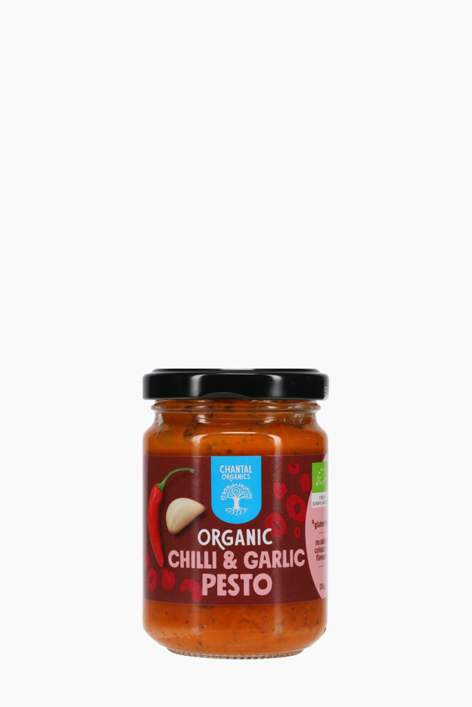 Jar of organic chili and garlic pesto on a white background