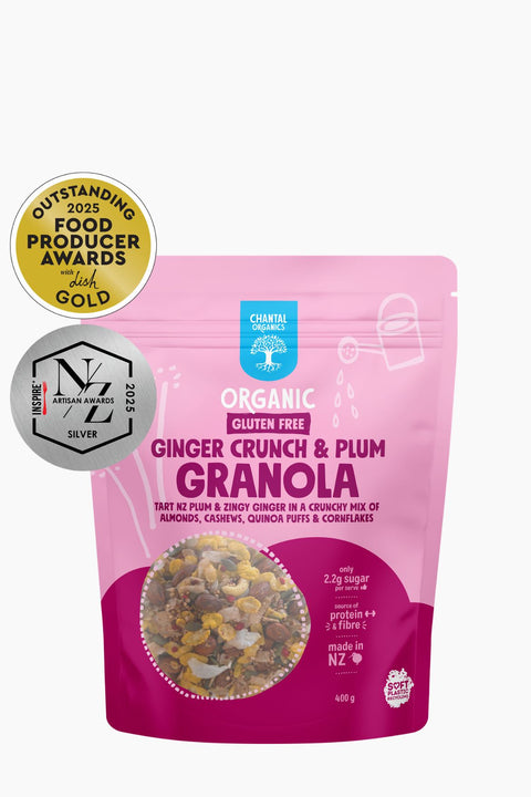 Pink package of ginger crunch & plum granola with awards on a white background