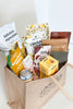 Assorted snacks in a tote bag on a white background
