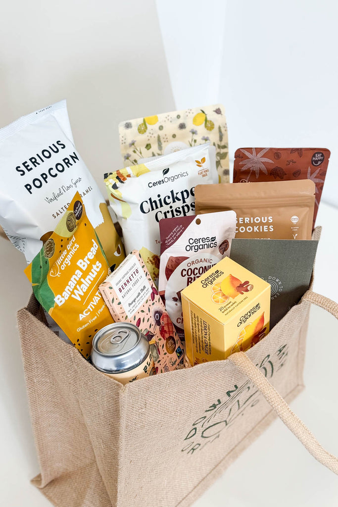 Assorted snacks in a tote bag on a white background