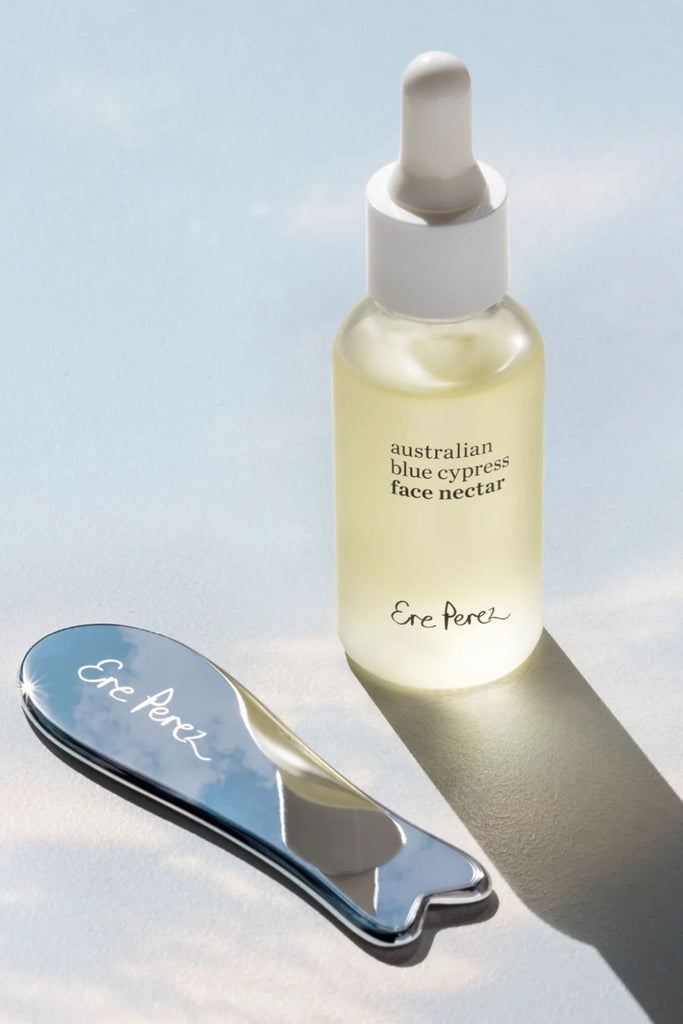 Bottle of 'australian blue cypress face nectar' with a dropper and a metal tool on a light background