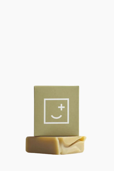 Bar of soap with a green box featuring a smiley face symbol on a white background