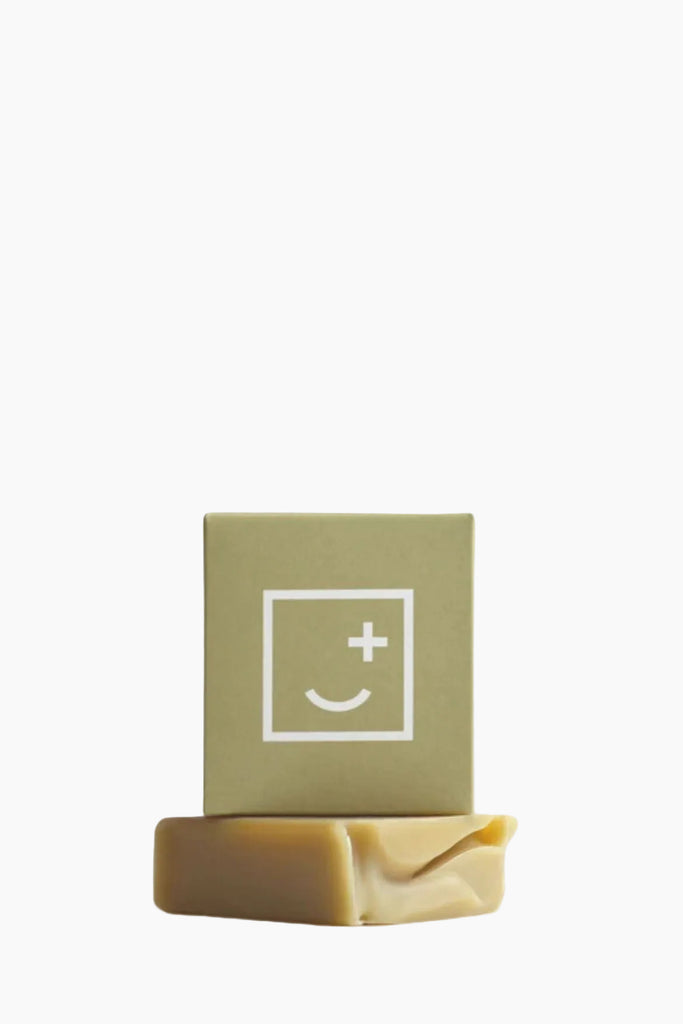 Bar of soap with a green box featuring a smiley face symbol on a white background