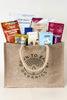 Jute bag filled with various snack packets on a light background