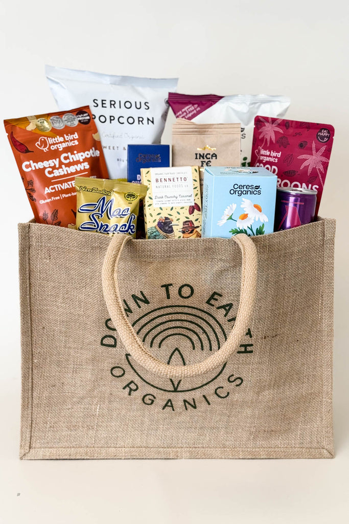 Jute bag filled with various snack packets on a light background