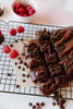 Chocolate cake with raspberries and chocolate chips on a cooling rack