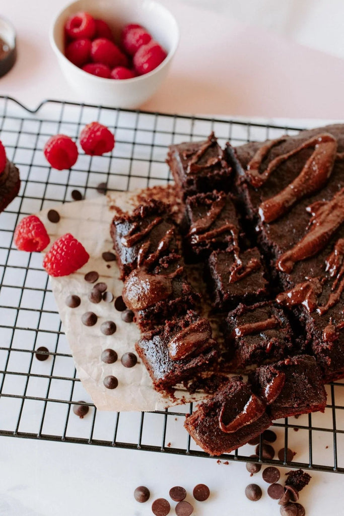 Chocolate cake with raspberries and chocolate chips on a cooling rack