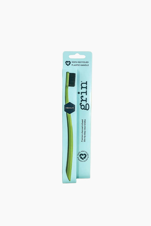 Green toothbrush in a blue packaging with 'grim' branding on a white background