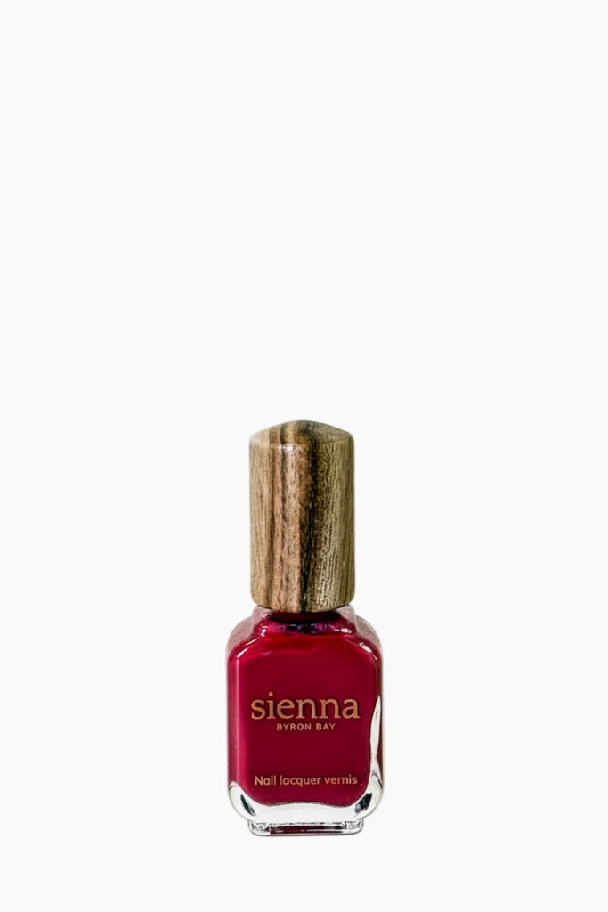 Red nail polish bottle with wooden cap on a white background