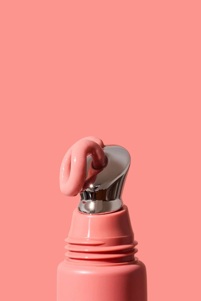Pink lip balm with silver cap on a pink background