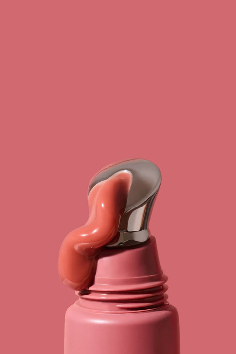 Pink lip balm with a silver cap on a pink background