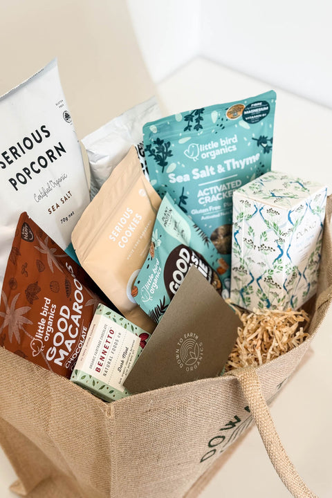 Plant-Based Gift Hamper ideas for birthdays, christmas, work Assorted snack packages including popcorn and crackers in a brown bag.