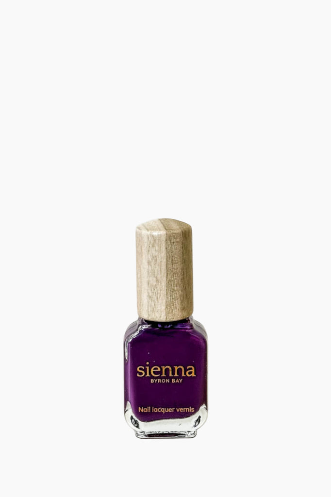 Purple nail polish bottle with wooden cap on a white background