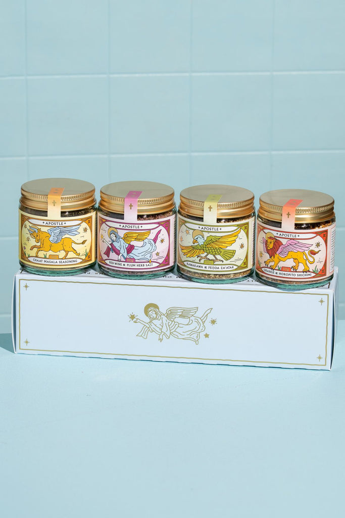 Four jars with decorative labels on a white box against a light blue tiled wall.