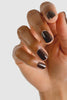 Close-up of a hand with dark brown nail polish on a light gray background