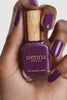 Purple nail polish bottle with wooden cap held by a hand with purple nails, brand 'sienna Byron Bay' visible.